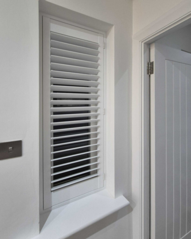 UK Made PVC Plantation Shutters for Landing Window in Manchester Beautifully fitted UK made white PVC plantation shutters installed in a landing window by Scarlet Blinds in Manchester, custom made for a perfect fit.
