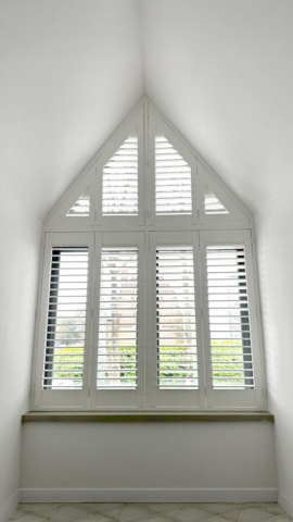 Wide Angle View of Arched PVC Plantation Shutters Wide angled view of an arched window fitted with UK made white PVC plantation shutters by Scarlet Blinds in Manchester, custom made for special shapes.