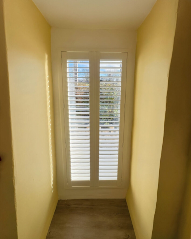 Full Height PVC Plantation Shutters for Upstairs Balcony Hallway White PVC plantation shutters fitted to a full height upstairs balcony hallway window, providing privacy and light control.