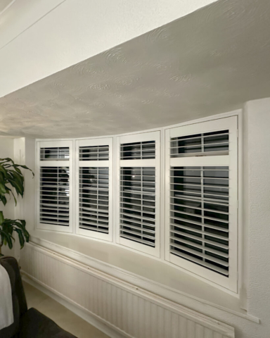 Slim Angled Bay Window PVC Plantation Shutters in Manchester Wide angled view of a slim angled bay window fitted with UK made white PVC plantation shutters by Scarlet Blinds in Manchester, custom made for special shapes.