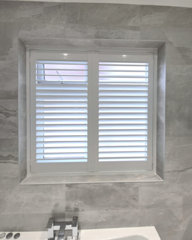 UK Made PVC Plantation Shutters for Bathroom Window in Oldham Bathroom window fitted with UK made white PVC plantation shutters by Scarlet Blinds and Shutters in Oldham, custom made for special shapes and moisture resistant use.