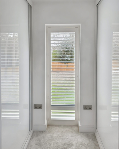UK Made PVC Plantation Shutters for Hallway Window in Wythenshawe Hallway window fitted with UK made white PVC plantation shutters by Scarlet Blinds and Shutters in Wythenshawe, custom made for a perfect fit.