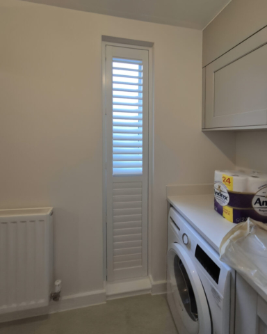 UK Made PVC Plantation Shutters for Slim Utility Window Beautifully fitted UK made white PVC plantation shutters installed on a slim tall utility window by Scarlet Blinds in Manchester, custom made for a perfect fit.