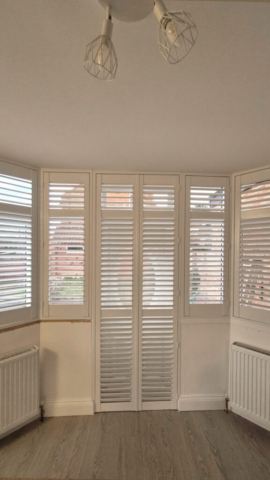 Plantation Shutters Fitted in Conservatory White PVC plantation shutters installed in a bright conservatory, providing light control and privacy, prodcut name Strato.