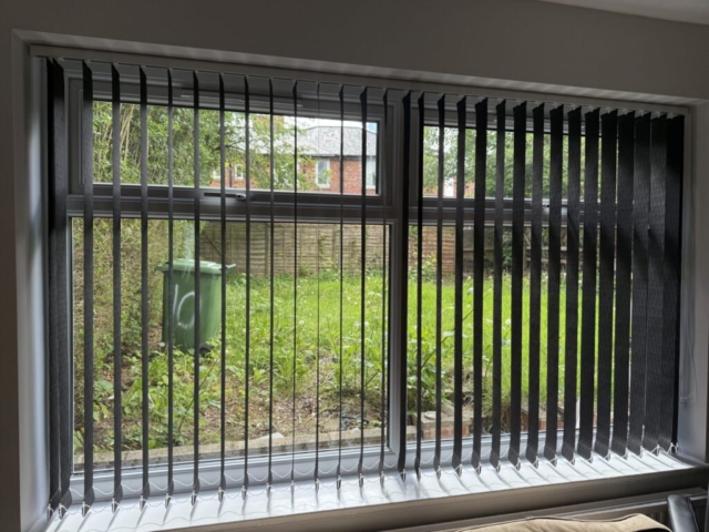 Black Vertical Blinds with Open Slats in Blackley, Manchester Black vertical blinds with open slats fitted to a large living room window in Blackley, Manchester